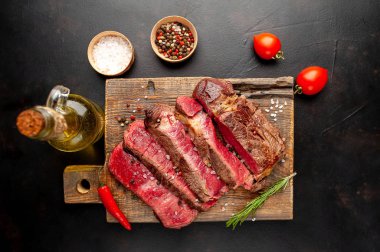 Siyah taş arka plan üzerinde ahşap doğrama tahtası üzerinde baharat ile Taze nadir ızgara beefsteak