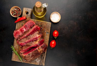 Siyah taş arka plan üzerinde ahşap doğrama tahtası üzerinde baharat ile Taze nadir ızgara beefsteak