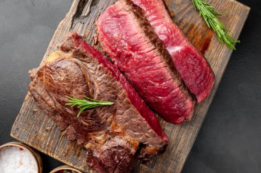 Siyah taş arka plan üzerinde ahşap doğrama tahtası üzerinde baharat ile Taze nadir ızgara beefsteak