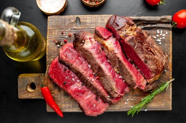 Siyah taş arka plan üzerinde ahşap doğrama tahtası üzerinde baharat ile Taze nadir ızgara beefsteak