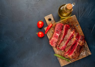 Siyah taş arka plan üzerinde ahşap doğrama tahtası üzerinde baharat ile Taze nadir ızgara beefsteak