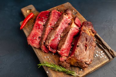 Siyah taş arka plan üzerinde ahşap doğrama tahtası üzerinde baharat ile Taze nadir ızgara beefsteak