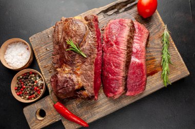 Siyah taş arka plan üzerinde ahşap doğrama tahtası üzerinde baharat ile Taze nadir ızgara beefsteak