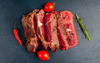 Siyah taş arka plan üzerinde baharat ile taze dilimlenmiş nadir ızgara beefsteak
