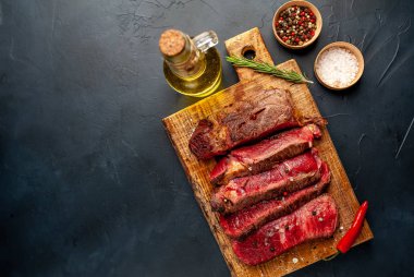 Siyah taş arka plan üzerinde ahşap doğrama tahtası üzerinde baharat ile Taze nadir ızgara beefsteak