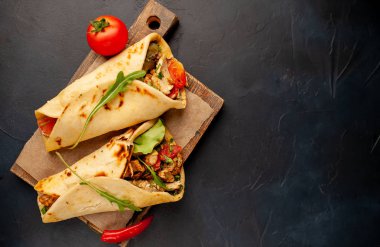 Siyah beton arka plan üzerinde ahşap doğrama tahtası üzerinde salata ile geleneksel Meksika tacos