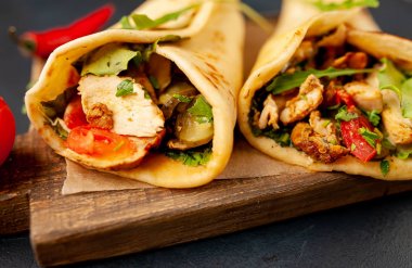 Siyah beton arka plan üzerinde ahşap doğrama tahtası üzerinde salata ile geleneksel Meksika tacos