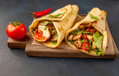 Siyah beton arka plan üzerinde ahşap doğrama tahtası üzerinde salata ile geleneksel Meksika tacos