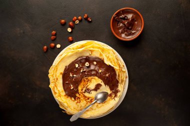 Siyah taş arka planda çikolatalı hamur ve fındık ile sunulan ev yapımı taze krep 