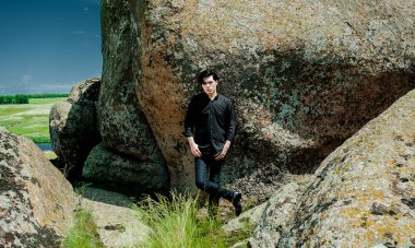 Siyah kıyafeti büyük kayalar üzerinde eğiliyor genç şık adam