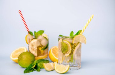 limonlimonata iki bardak, limon ve nane yaprakları, buz küpleri ve beyaz pipetler