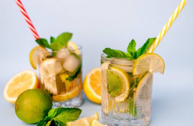 limonlimonata iki bardak, limon ve nane yaprakları, buz küpleri ve beyaz pipetler