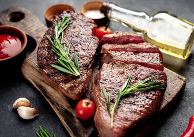 Baharatlı çiğ biftek ve siyah arkaplanda otlar.