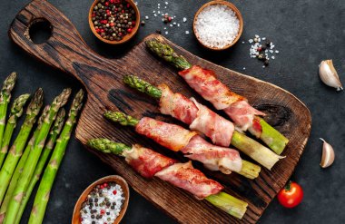 Pastırma ve baharatla pişirilmiş kuşkonmaz kesme tahtasının üzerinde.