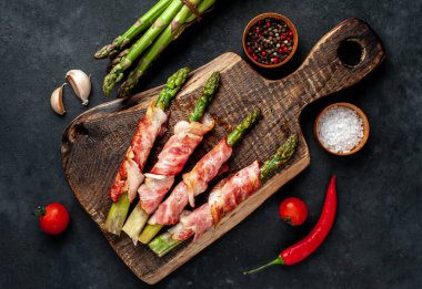 Pastırma ve baharatla pişirilmiş kuşkonmaz kesme tahtasının üzerinde.