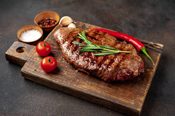 raw beef steak with spices on a wooden cutting board