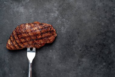 Siyah taşlı arka planda yağlı ızgara biftek.