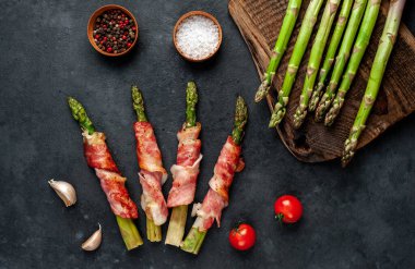 Pastırmalı ve baharatlı kuşkonmaz siyah arka planda kesilmiş tahtada.