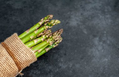 Siyah taş zemin üzerinde ham yeşil kuşkonmaz ve kopyalama alanı 