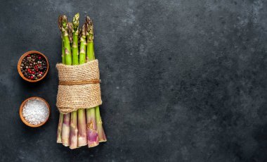 Siyah taş zemin üzerinde ham yeşil kuşkonmaz ve kopyalama alanı 