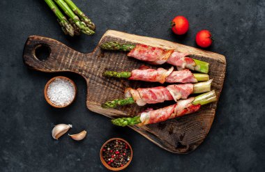 Pastırmalı kuşkonmaz ve siyah arka planda baharat.