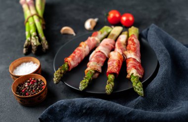 Pastırmalı kuşkonmaz ve siyah arka planda baharat.