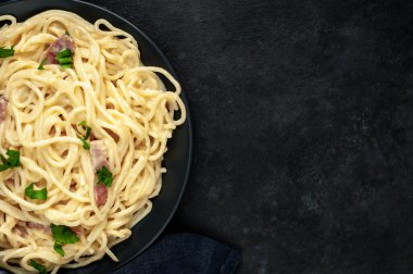 Pastırmalı spagetti ve siyah arka planda peynir.