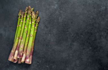 Siyah taş zemin üzerinde ham yeşil kuşkonmaz ve kopyalama alanı 