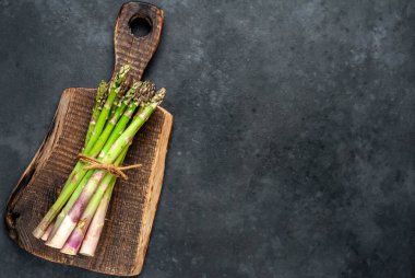 Siyah taş zemin üzerinde ham yeşil kuşkonmaz ve kopyalama alanı 