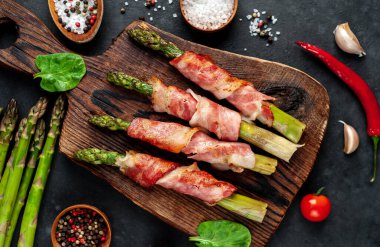 Pastırmalı ve baharatlı kuşkonmaz siyah arka planda kesilmiş tahtada.