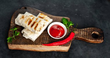 Geleneksel Meksika dürümü. Siyah arka planda baharatlı soslu tavuk ve sebzeyle sarılmış.