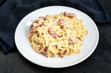 Pastırmalı spagetti ve siyah arka planda peynir.