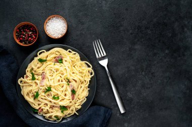 Pastırmalı spagetti ve siyah arka planda peynir.