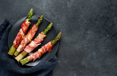 Pastırmalı kuşkonmaz ve siyah arka planda baharat.