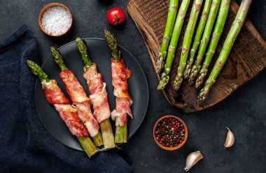 Pastırmalı kuşkonmaz ve siyah arka planda baharat.