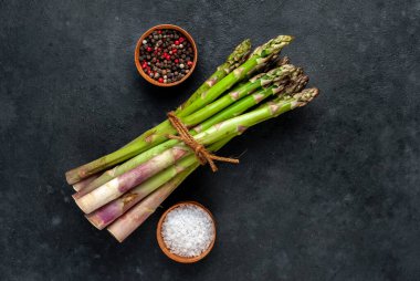 Siyah taş zemin üzerinde ham yeşil kuşkonmaz ve kopyalama alanı 