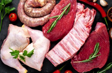 Baharatlı çiğ et ve siyah arka planda bitkiler