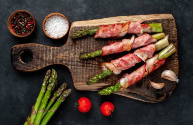 Pastırmalı kuşkonmaz ve siyah arka planda baharat.