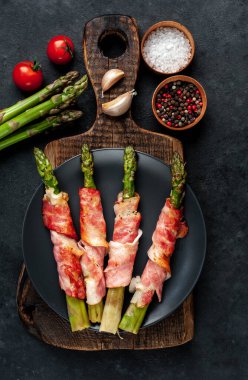 Pastırmalı kuşkonmaz ve siyah arka planda baharat.