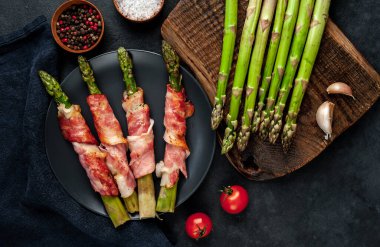 Pastırmalı kuşkonmaz ve siyah arka planda baharat.