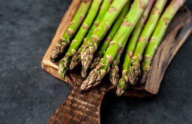 Siyah taş zemin üzerinde ham yeşil kuşkonmaz ve kopyalama alanı 