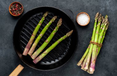 Siyah taş zemin üzerinde ham yeşil kuşkonmaz ve kopyalama alanı 