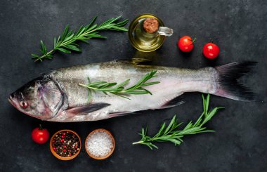 Siyah zemin üzerinde biberiye, domates, biber ve tuz olan gümüş sazan balığı.