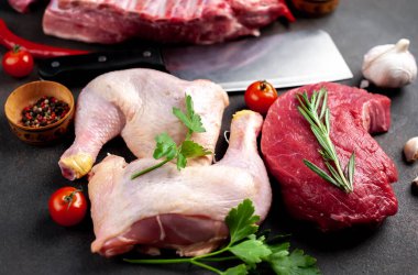 Farklı et türleri. Siyah arka planda sebze ve baharatla süslenmiş taze et.