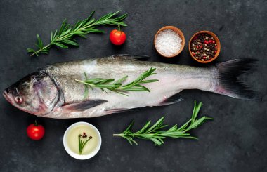 Siyah zemin üzerinde biberiye, domates, biber ve tuz olan gümüş sazan balığı.