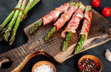 Pastırmalı kuşkonmaz ve siyah arka planda baharat.