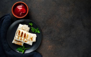 Geleneksel Meksika dürümü. Siyah arka planda baharatlı soslu tavuk ve sebzeyle sarılmış.