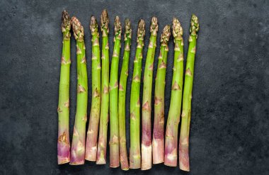 Siyah taş zemin üzerinde ham yeşil kuşkonmaz ve kopyalama alanı 