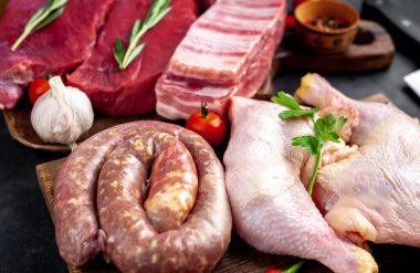 Baharatlı çiğ et ve siyah arka planda bitkiler