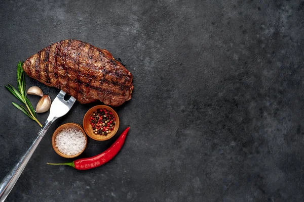 Fatty grilled beef steak on black stone background